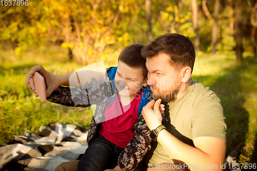 Image of Father and son walking and having fun in autumn forest, look happy and sincere