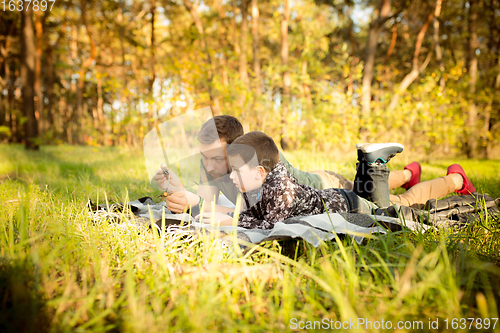 Image of Father and son walking and having fun in autumn forest, look happy and sincere