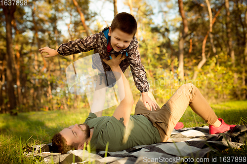 Image of Father and son walking and having fun in autumn forest, look happy and sincere