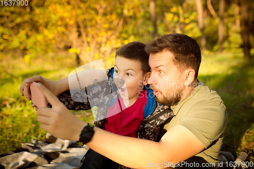 Image of Father and son walking and having fun in autumn forest, look happy and sincere