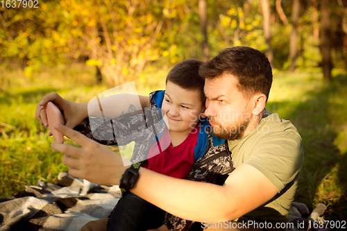 Image of Father and son walking and having fun in autumn forest, look happy and sincere