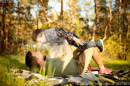 Image of Father and son walking and having fun in autumn forest, look happy and sincere