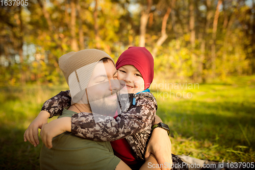 Image of Father and son walking and having fun in autumn forest, look happy and sincere