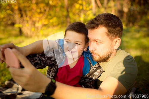 Image of Father and son walking and having fun in autumn forest, look happy and sincere