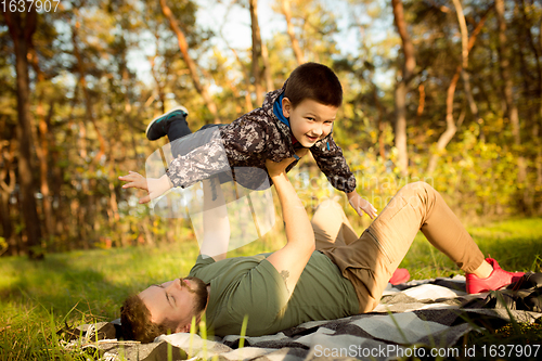 Image of Father and son walking and having fun in autumn forest, look happy and sincere