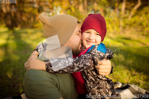 Image of Father and son walking and having fun in autumn forest, look happy and sincere