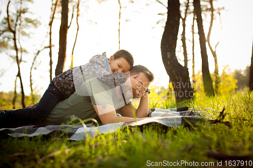 Image of Father and son walking and having fun in autumn forest, look happy and sincere