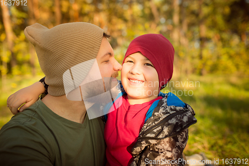 Image of Father and son walking and having fun in autumn forest, look happy and sincere