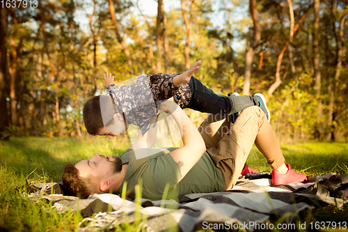 Image of Father and son walking and having fun in autumn forest, look happy and sincere