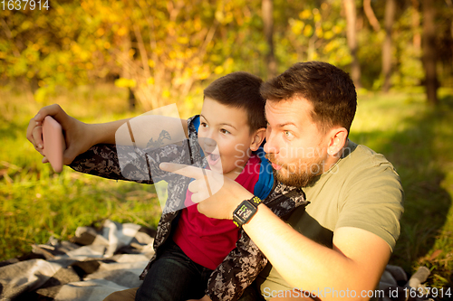 Image of Father and son walking and having fun in autumn forest, look happy and sincere