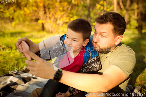 Image of Father and son walking and having fun in autumn forest, look happy and sincere