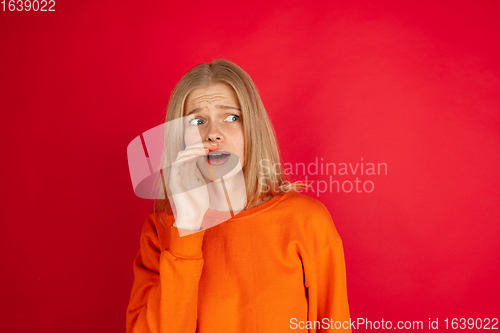 Image of Portrait of young caucasian woman with bright emotions isolated on red studio background