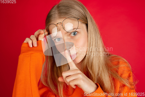 Image of Portrait of young caucasian woman with bright emotions isolated on red studio background