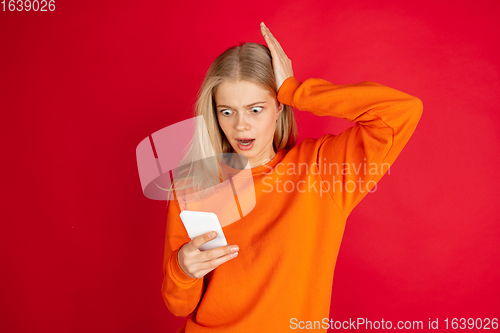 Image of Portrait of young caucasian woman with bright emotions isolated on red studio background