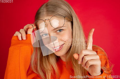 Image of Portrait of young caucasian woman with bright emotions isolated on red studio background