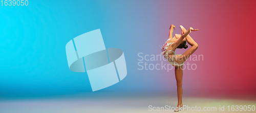 Image of Little caucasian girl, rhytmic gymnast training, performing isolated on gradient blue-red studio background in neon