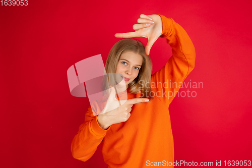 Image of Portrait of young caucasian woman with bright emotions isolated on red studio background