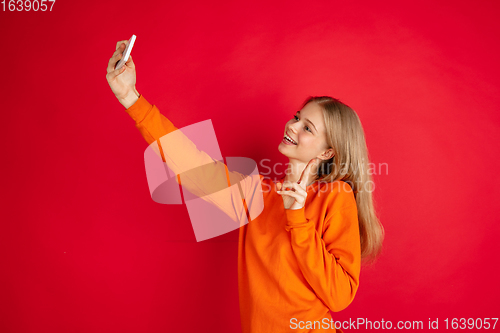 Image of Portrait of young caucasian woman with bright emotions isolated on red studio background