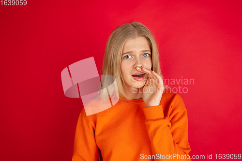 Image of Portrait of young caucasian woman with bright emotions isolated on red studio background