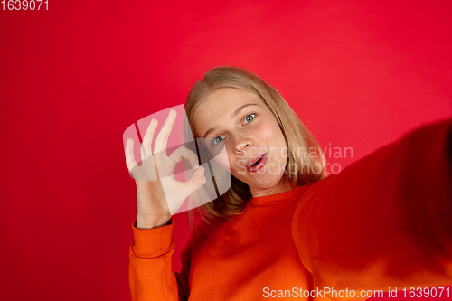 Image of Portrait of young caucasian woman with bright emotions isolated on red studio background