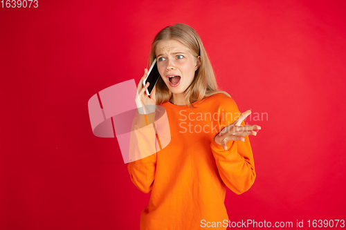 Image of Portrait of young caucasian woman with bright emotions isolated on red studio background