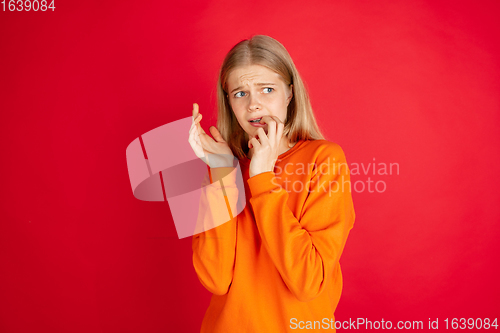 Image of Portrait of young caucasian woman with bright emotions isolated on red studio background