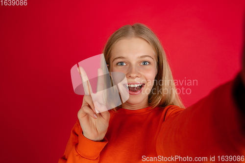 Image of Portrait of young caucasian woman with bright emotions isolated on red studio background