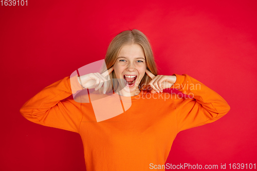 Image of Portrait of young caucasian woman with bright emotions isolated on red studio background