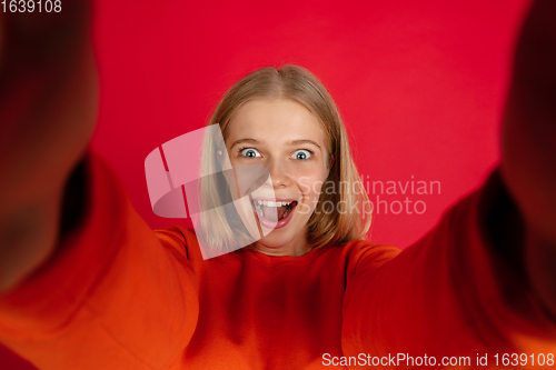 Image of Portrait of young caucasian woman with bright emotions isolated on red studio background