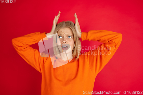 Image of Portrait of young caucasian woman with bright emotions isolated on red studio background