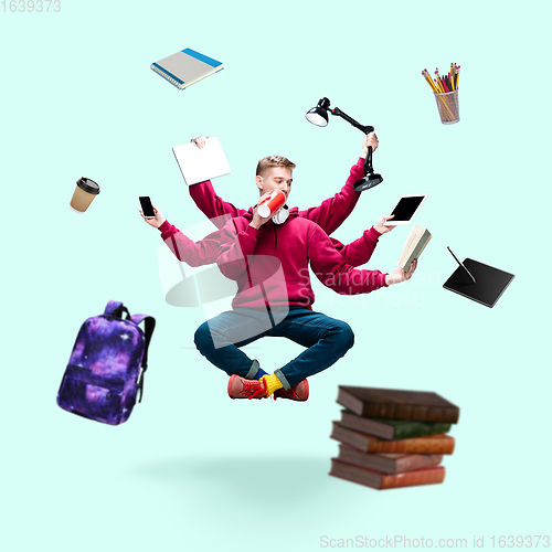 Image of Handsome multi-armed student levitating isolated on blue studio background with equipment