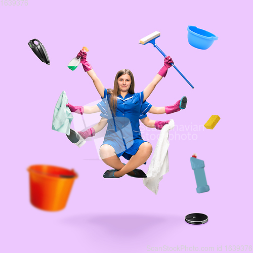 Image of Handsome multi-armed housemaid levitating isolated on pink studio background with equipment