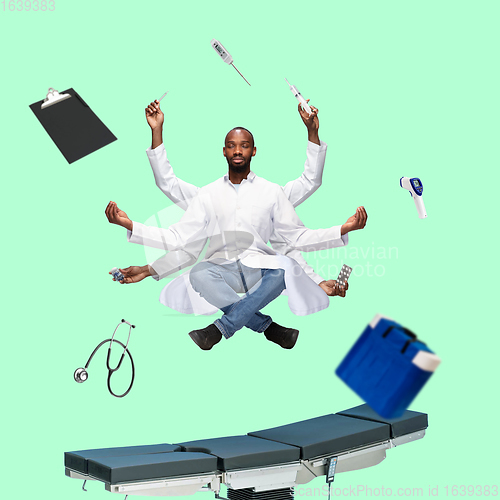 Image of Handsome multi-armed doctor levitating isolated on green studio background with equipment