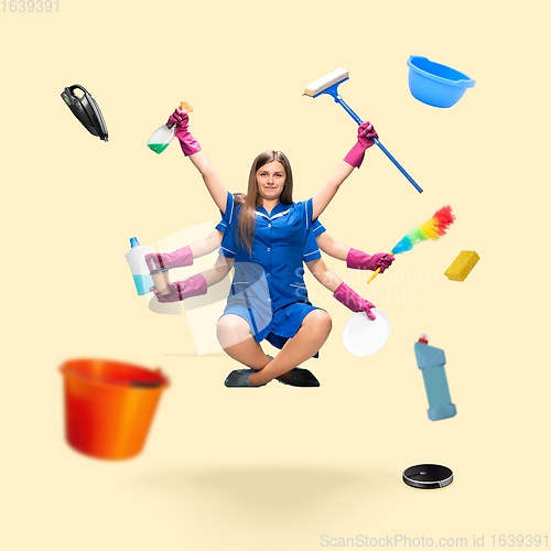 Image of Handsome multi-armed housemaid levitating isolated on yellow studio background with equipment