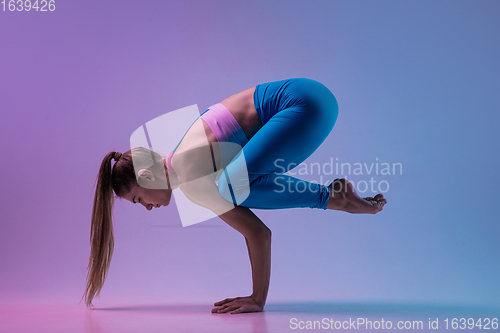 Image of Young sportive woman training isolated on gradient studio background in neon light. athletic and graceful