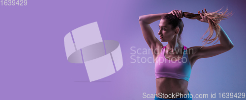 Image of Young sportive woman training isolated on gradient studio background in neon light. athletic and graceful