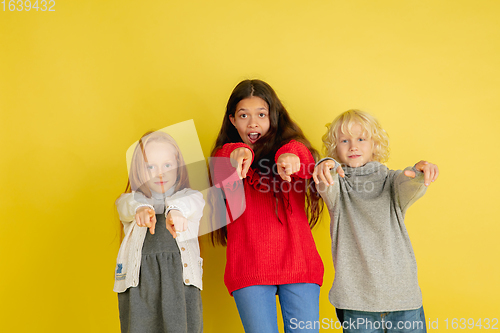 Image of Portrait of little caucasian children with bright emotions isolated on yellow studio background