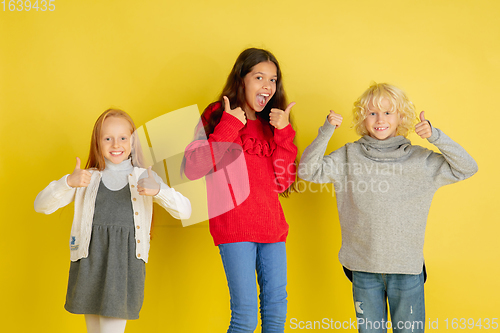 Image of Portrait of little caucasian children with bright emotions isolated on yellow studio background