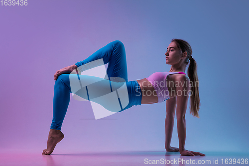 Image of Young sportive woman training isolated on gradient studio background in neon light. athletic and graceful