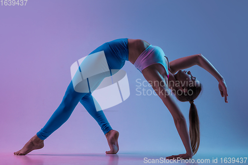 Image of Young sportive woman training isolated on gradient studio background in neon light. athletic and graceful