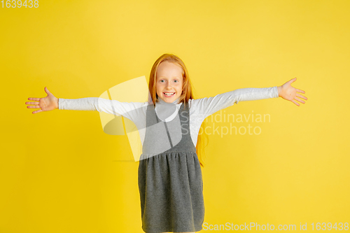 Image of Portrait of little caucasian girl with bright emotions isolated on yellow studio background