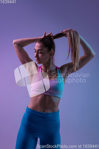 Image of Young sportive woman training isolated on gradient studio background in neon light. athletic and graceful