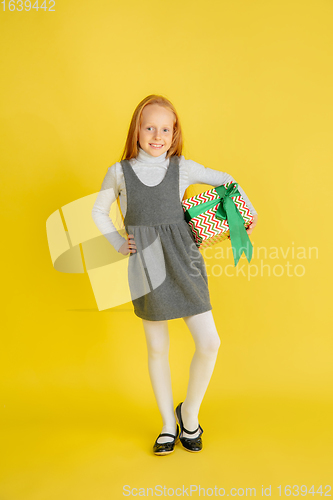 Image of Giving and getting presents on Christmas holidays. Teen girl having fun isolated on yellow studio background