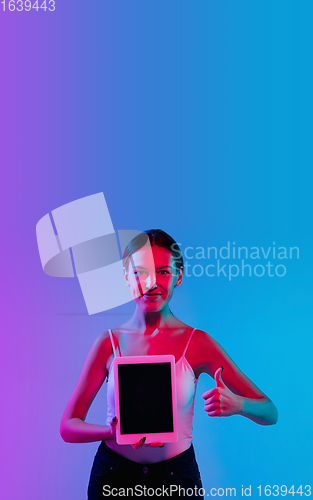 Image of Young caucasian woman\'s portrait on gradient blue-purple studio background in neon light