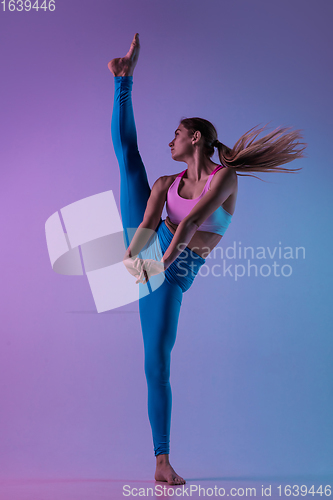 Image of Young sportive woman training isolated on gradient studio background in neon light. athletic and graceful