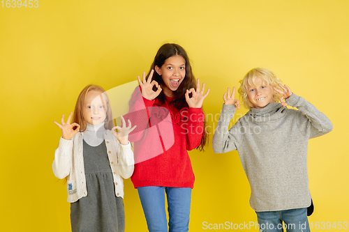 Image of Portrait of little caucasian children with bright emotions isolated on yellow studio background