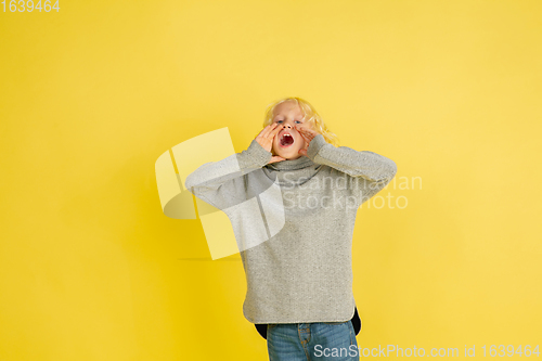 Image of Portrait of little caucasian boy with bright emotions isolated on yellow studio background