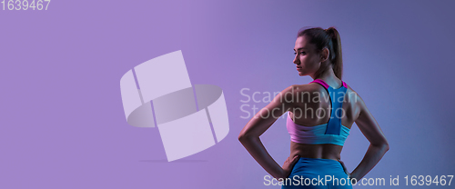 Image of Young sportive woman training isolated on gradient studio background in neon light. athletic and graceful