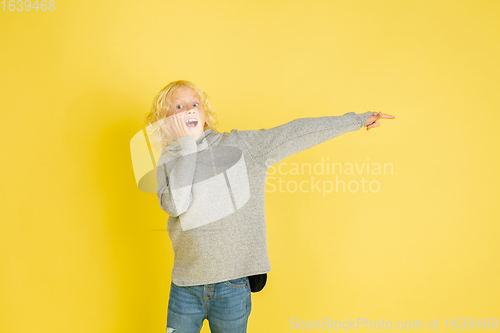 Image of Portrait of little caucasian boy with bright emotions isolated on yellow studio background