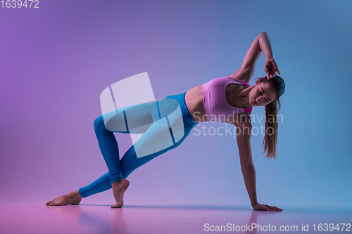 Image of Young sportive woman training isolated on gradient studio background in neon light. athletic and graceful
